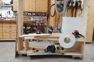 Werkbank mit verschiedenen Elektrowerkzeugen und großem weißen Klebeband in einer Holzwerkstatt.